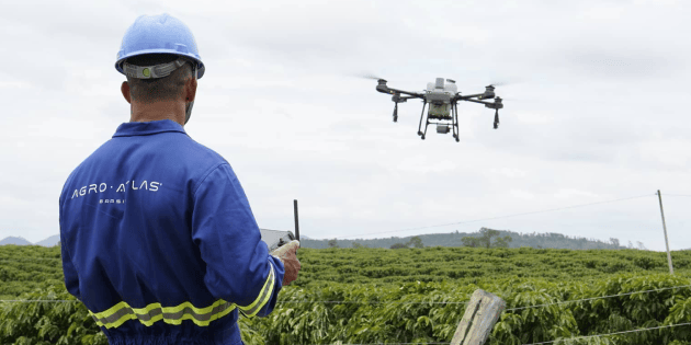 Operador Agro Atlas voando drone sobre o campo